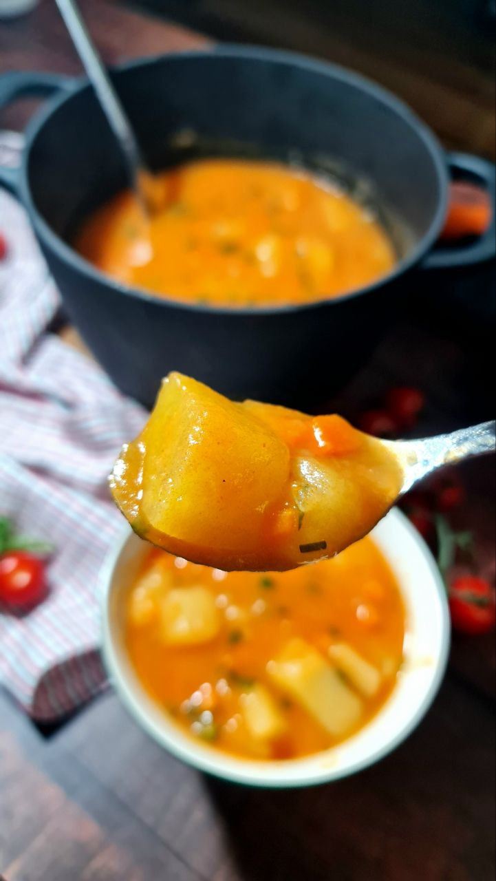 Potato stew in tablespoon and in a pot. 
Vegan potato stew.