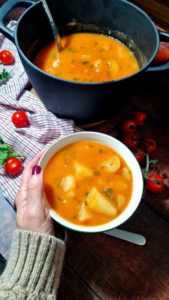 Vegan cmfort food, hand bowl with potato soup, cherry tomatoes. pot with potato stew, vegan recipe