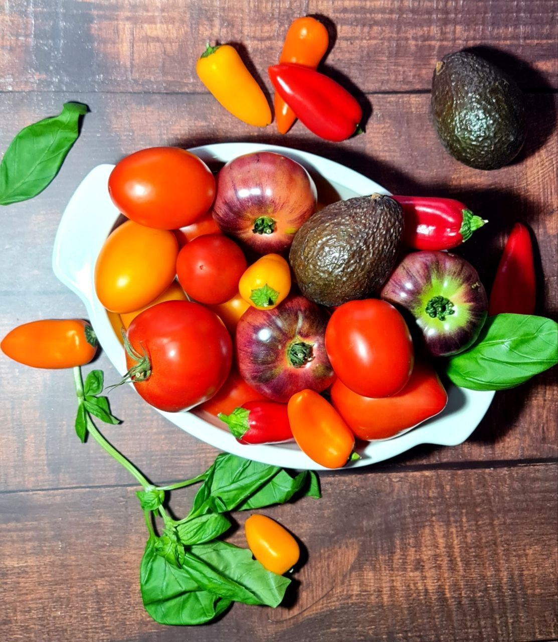 Assorted colorful vegetables and vegan cooking ingredients on a wooden kitchen counter.