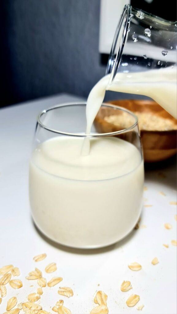 glass with homemade oat milk, pour oat milk into a glass.