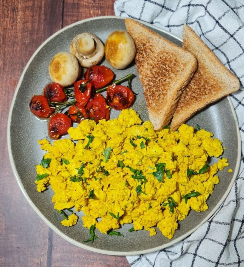 tofu scramble serving with cherry tomatoes, mushrooms and slice of bread