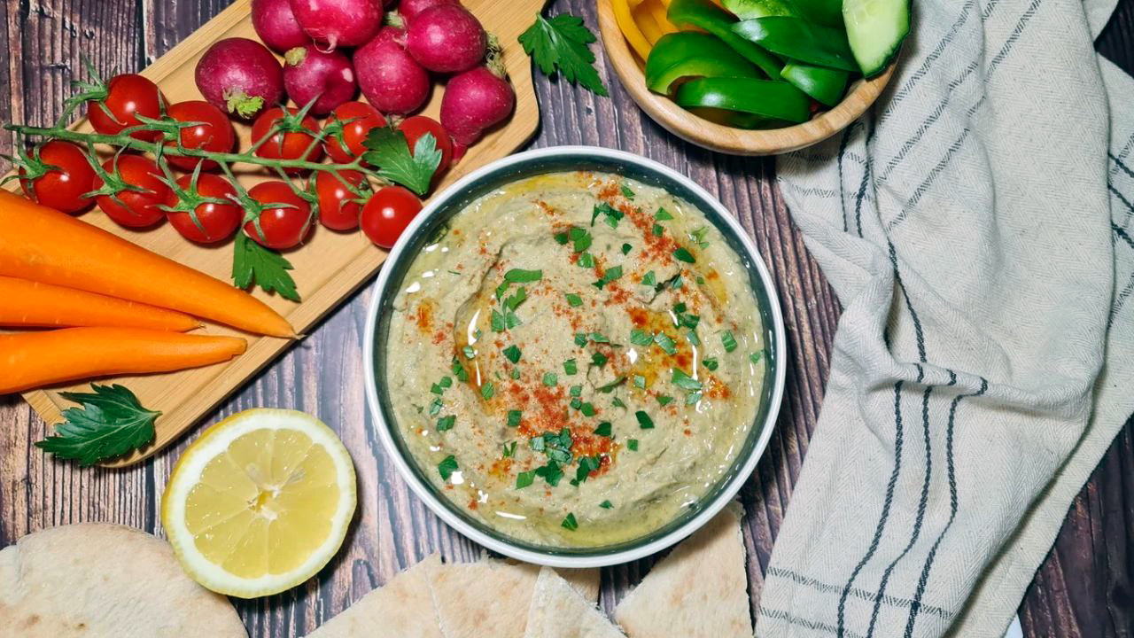 Bowl of hummus with fresh vegetables and pita bread