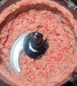 Close-up view of blended watermelon slushie mixture in a food processor.