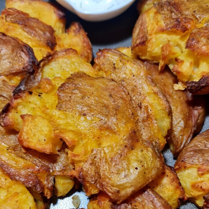 Crispy smashed potatoes with a side of creamy dipping sauce.