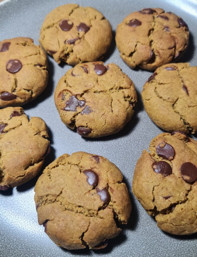 A plate of freshly baked vegan matcha chocolate chip cookies with a golden-brown color and chocolate chips.