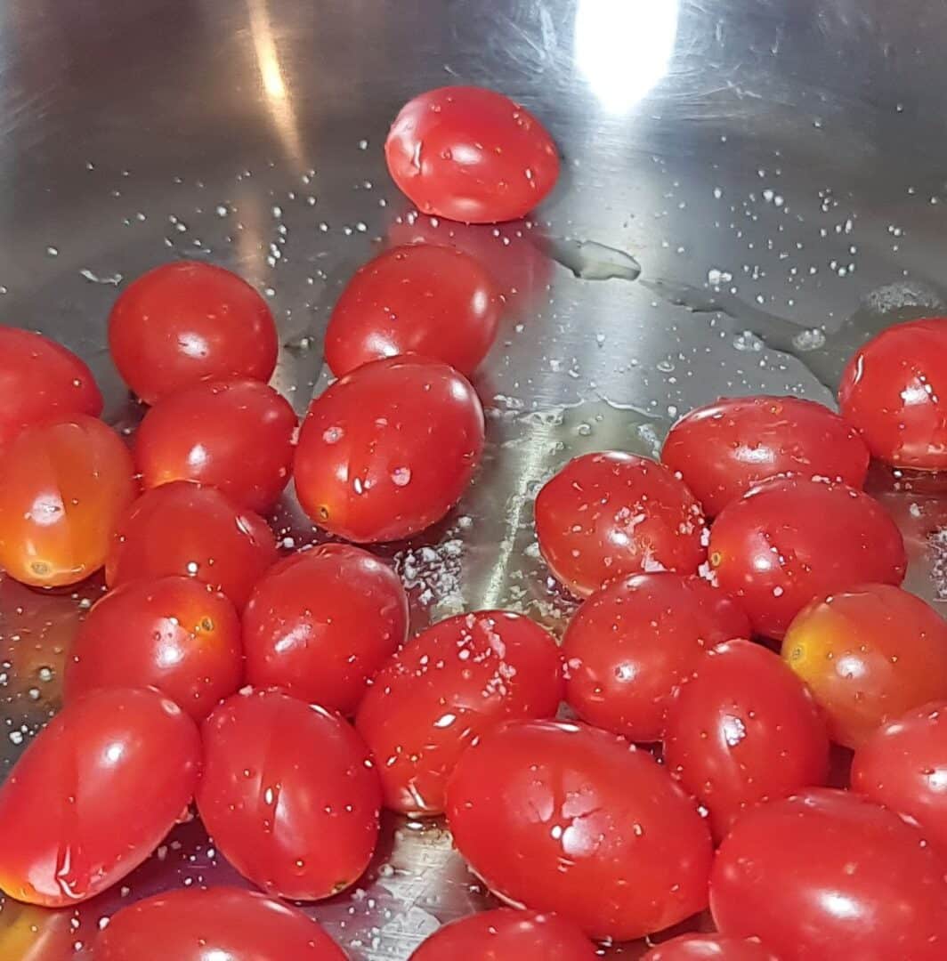 Cherry tomatoes being roasted in a pan with a sprinkle of sea salt. Cherry tomatoes roasting with sea salt, ready to top the avocado toast.