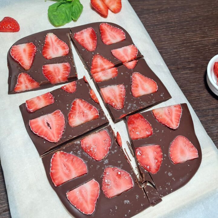 Chocolate peanut butter strawberry bark cut into squares on parchment paper. Delicious chocolate peanut butter strawberry bark, sliced into convenient squares for easy snacking.