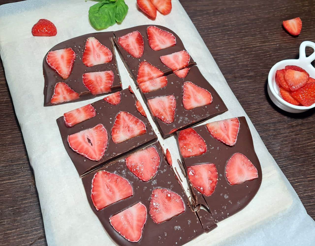 Chocolate peanut butter strawberry bark cut into squares on parchment paper. Delicious chocolate peanut butter strawberry bark, sliced into convenient squares for easy snacking.