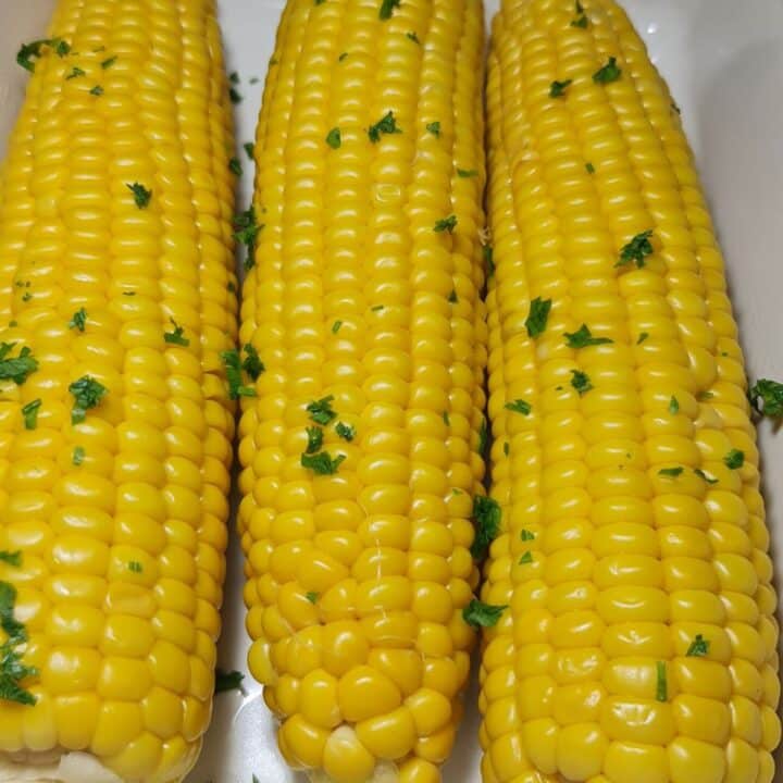 Close-up view of boiled corn on the cob with parsley garnish