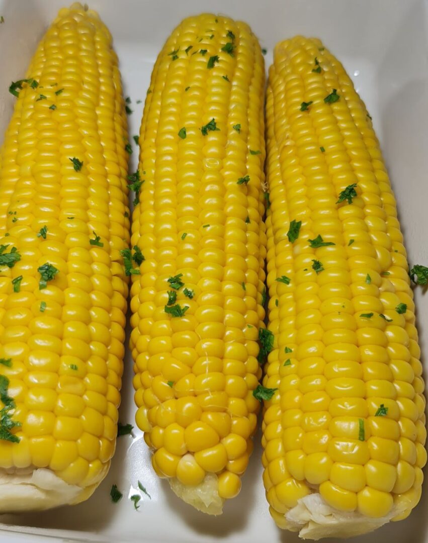 Close-up view of boiled corn on the cob with parsley garnish