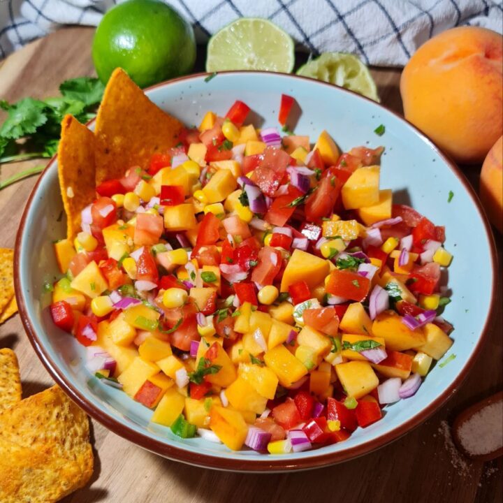 Fresh and colorful peach salsa with tomatoes, red onions, corn, and bell peppers in a bowl.