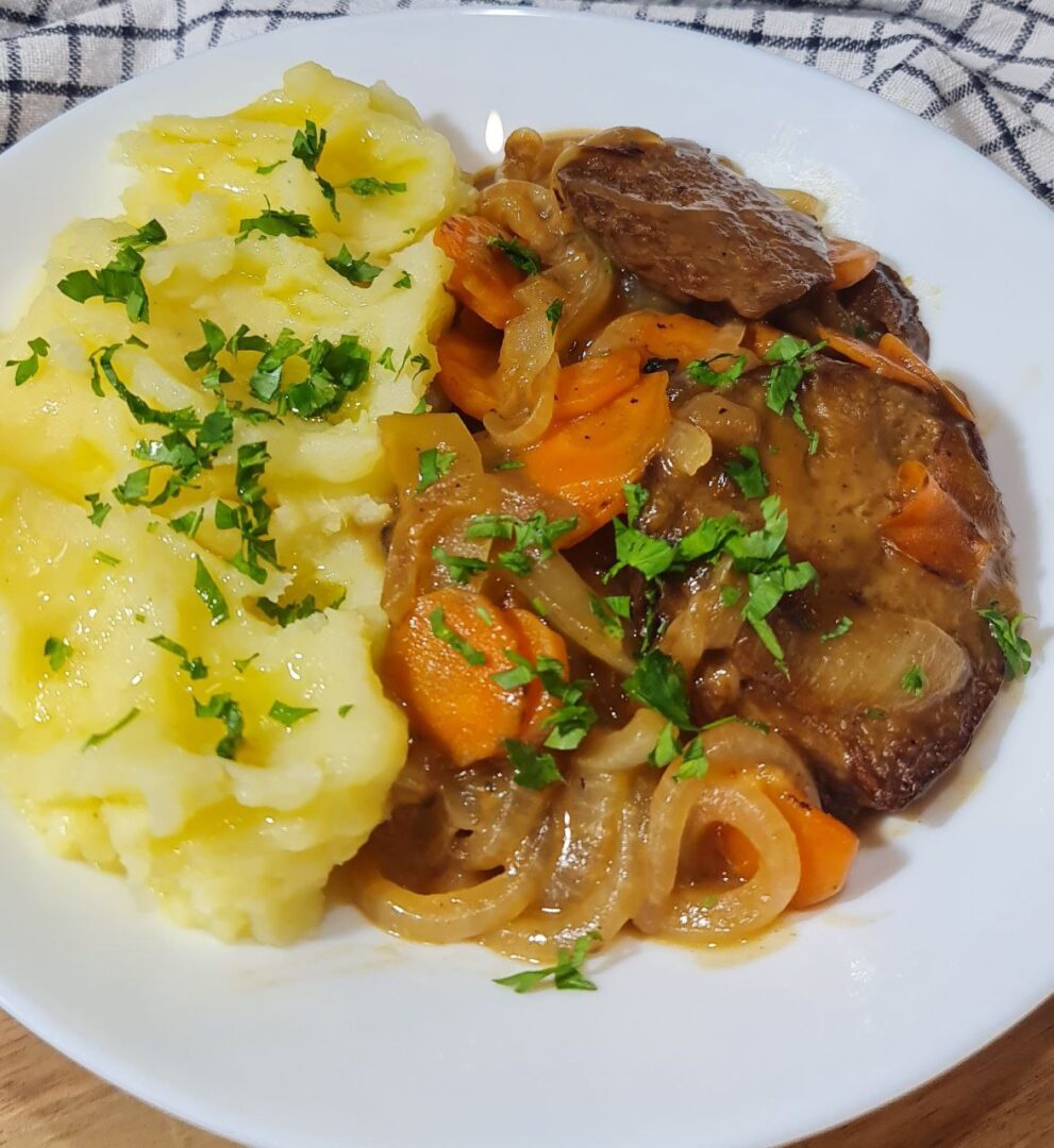 Close-up of savory seitan with wine sauce, mashed potatoes, and toasted bread. A close-up view of savory seitan with wine sauce, paired with creamy mashed potatoes and toasted bread.