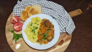 Plate of savory seitan with wine sauce, mashed potatoes, toasted bread, and fresh tomatoes. :A delicious meal of savory seitan with wine sauce served with mashed potatoes, toasted bread, and fresh tomatoes.