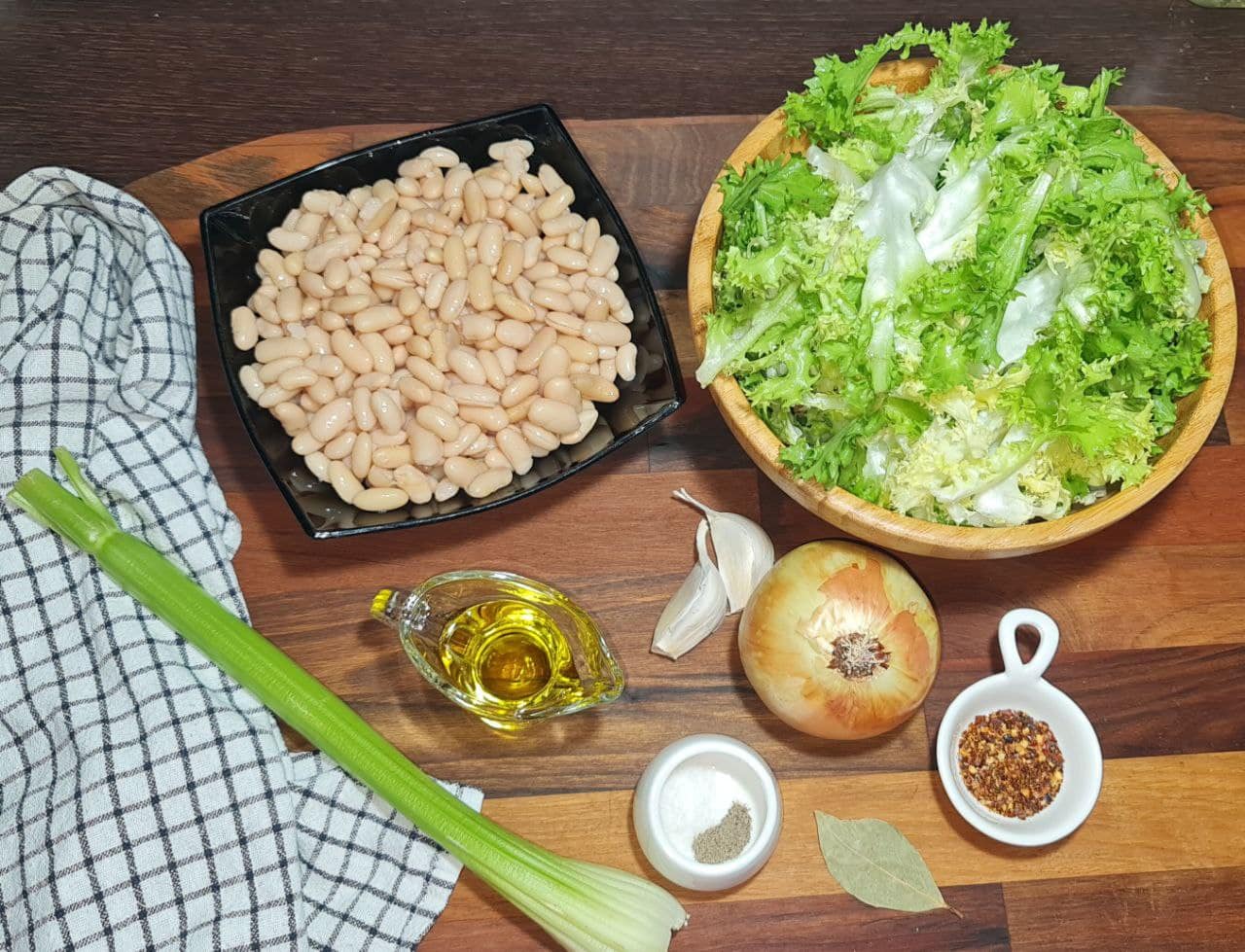 a bowl of beans and lettuce on a wooden surface