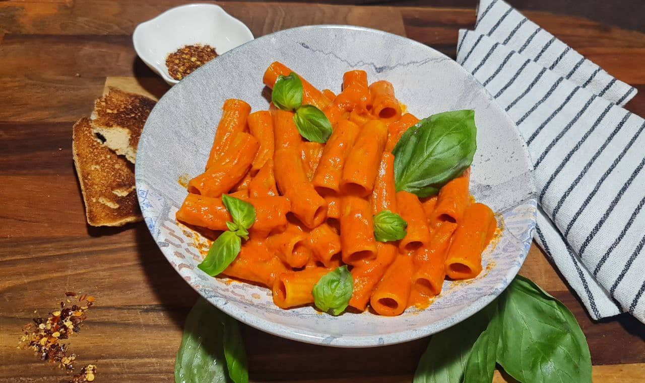 a plate of pasta with sauce and basil leaves