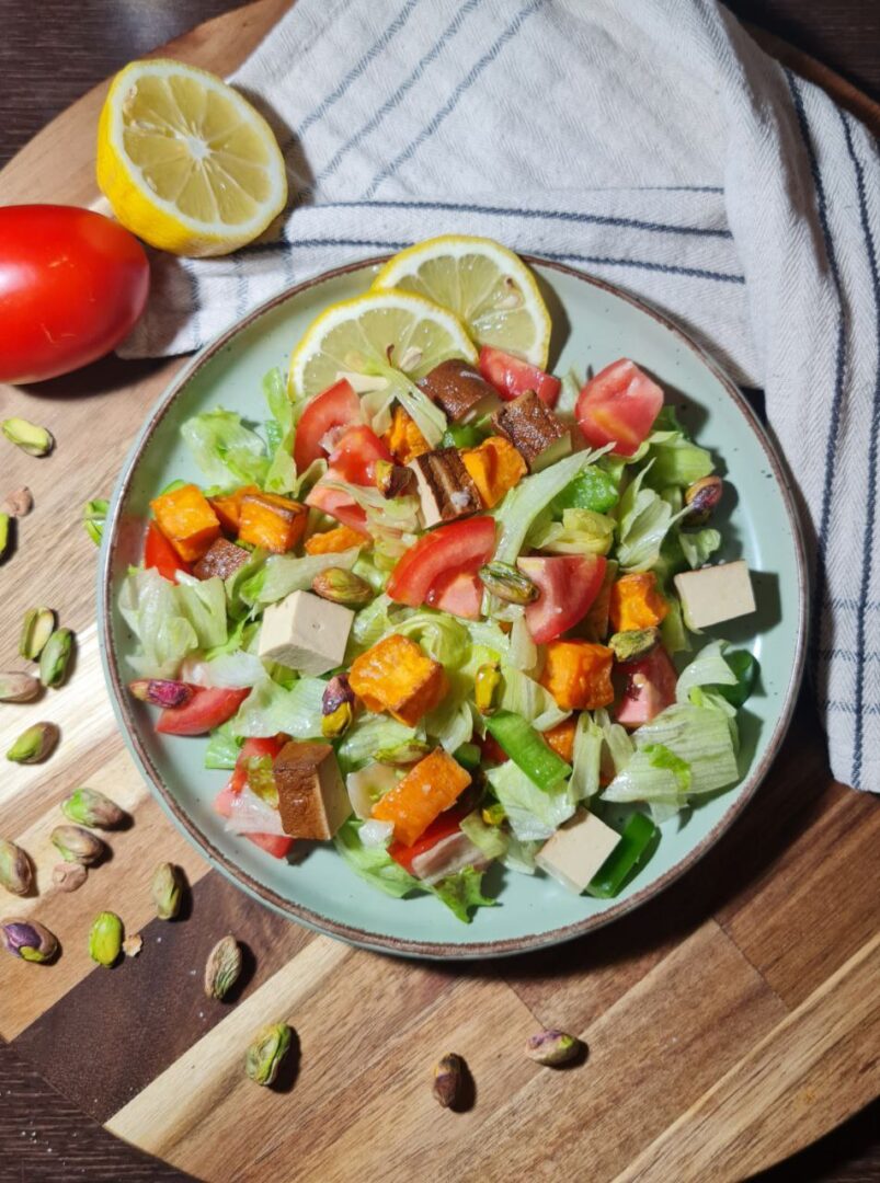 a plate of smoked tofu sweet potato salad with vegetables and lemons