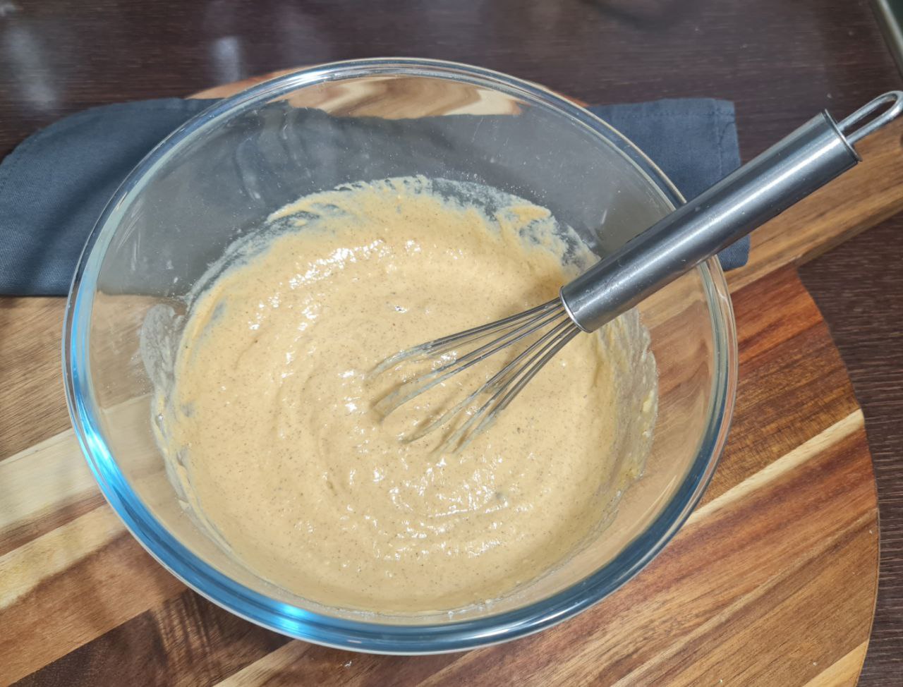 Vegan pumpkin pancake batter whisked in a glass bowl. Whisking the vegan pumpkin pancake batter to a smooth consistency.