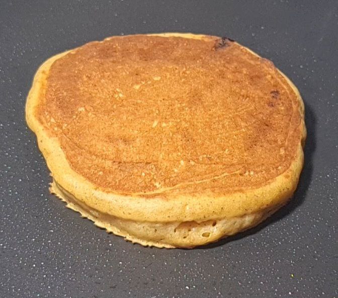 Vegan pumpkin pancake cooking on a non-stick pan. Vegan pumpkin pancake cooked to a golden-brown perfection.