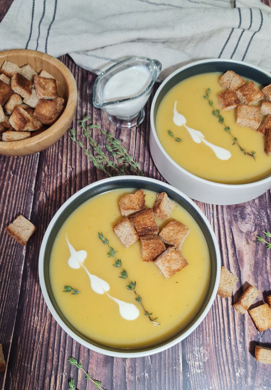 bowls of creamy carlic potato soup with croutons and herbs