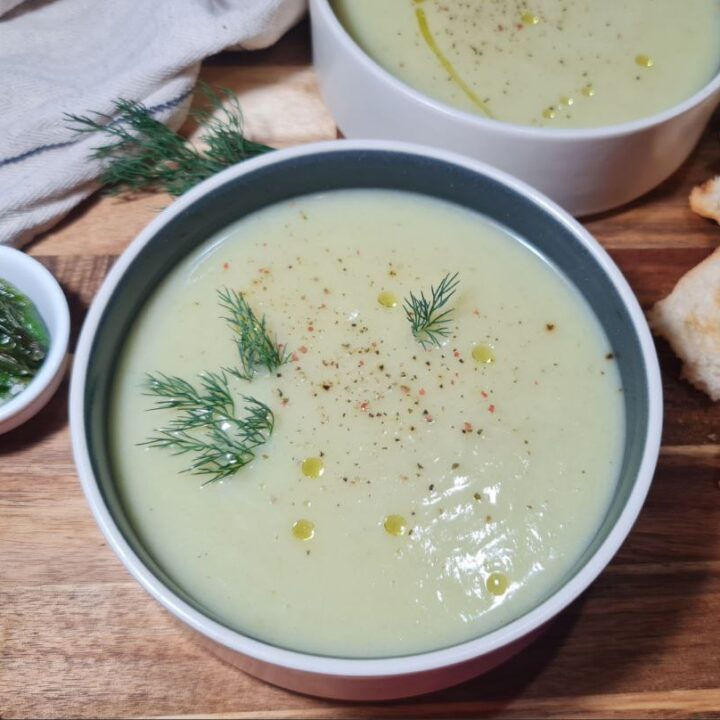 Bowl of creamy vegan cauliflower and fennel soup garnished with fresh dill, paired with roasted peppers and toasted bread. A comforting bowl of creamy vegan cauliflower and fennel soup, garnished with fresh dill, served with roasted peppers and toasted bread.