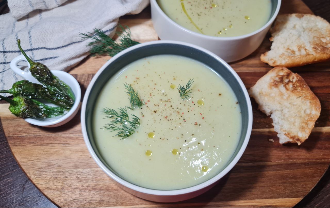 Bowl of creamy vegan cauliflower and fennel soup garnished with fresh dill, paired with roasted peppers and toasted bread. A comforting bowl of creamy vegan cauliflower and fennel soup, garnished with fresh dill, served with roasted peppers and toasted bread.