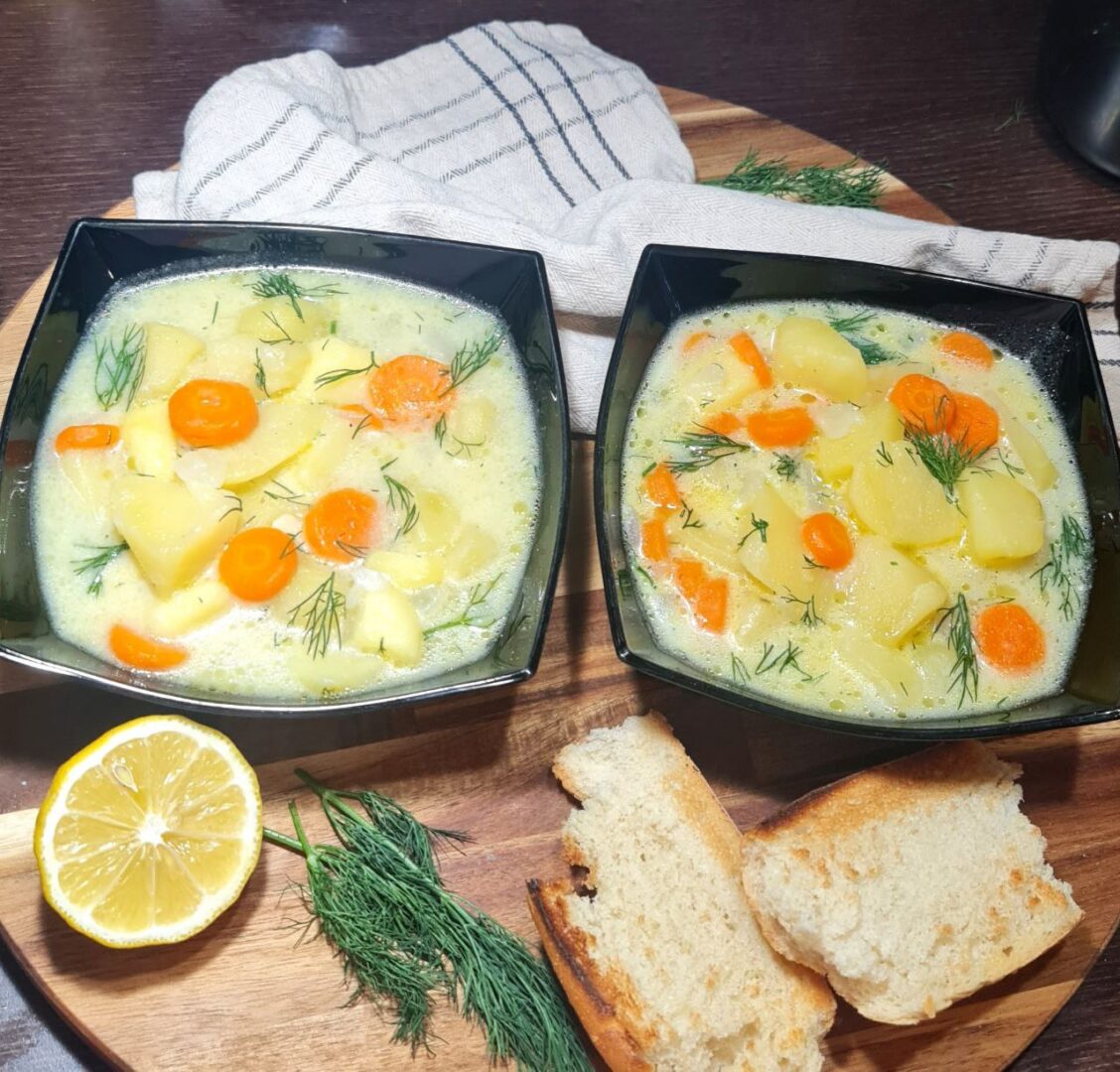 two bowls of soup and bread on a wooden tray