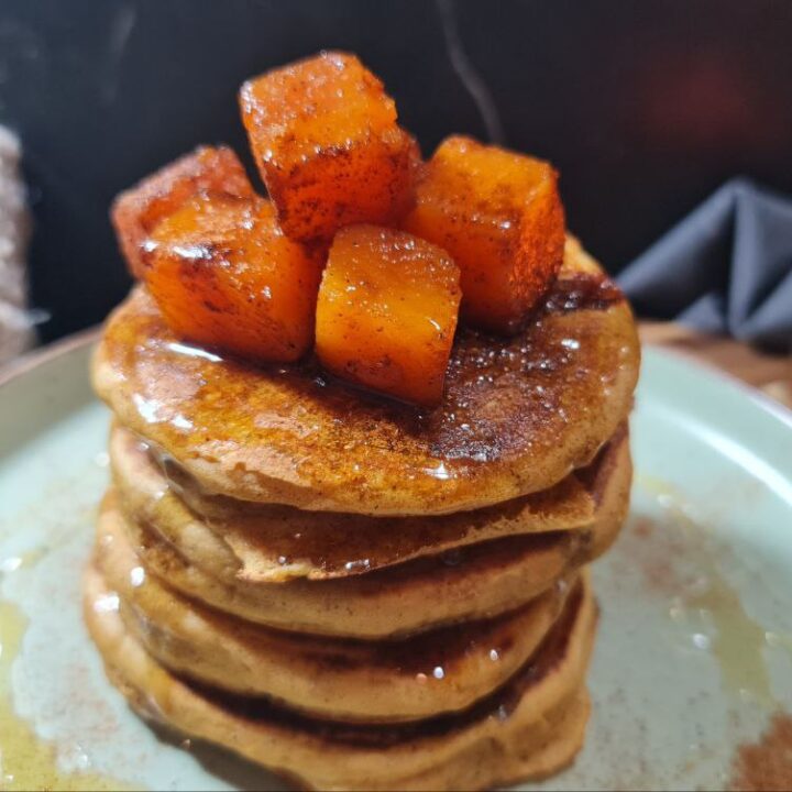 a stack of pancakes with orange cubes on top