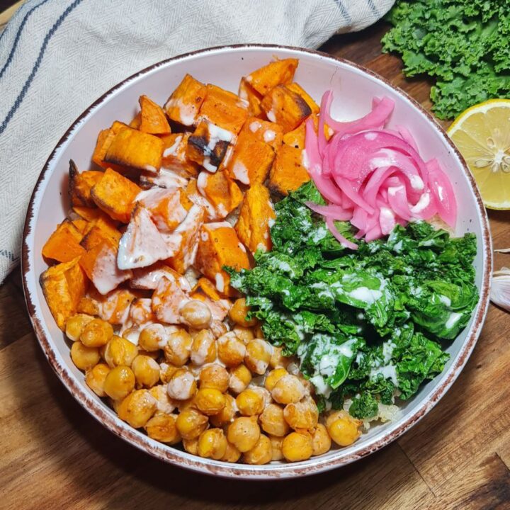 Vegan quinoa bowl with roasted sweet potatoes, chickpeas, sautéed kale, pickled onions, and tahini sauce. A vibrant vegan quinoa bowl featuring roasted sweet potatoes, chickpeas, sautéed kale, and pickled onions drizzled with a creamy tahini sauce.