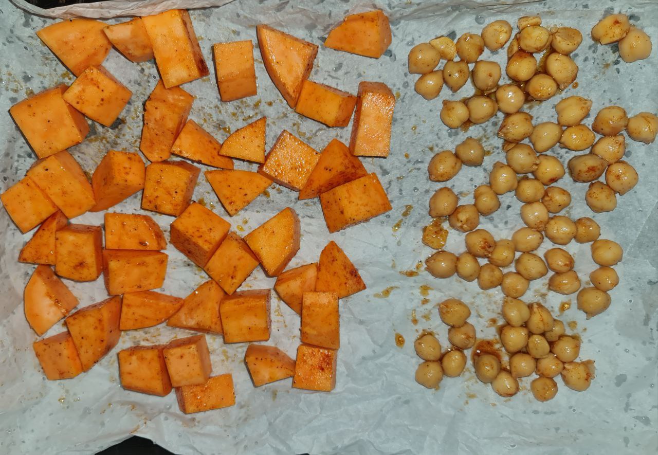  Roasted sweet potato cubes and seasoned chickpeas on a baking sheet.  Prepping the roasted sweet potatoes and chickpeas for a hearty vegan quinoa bowl.