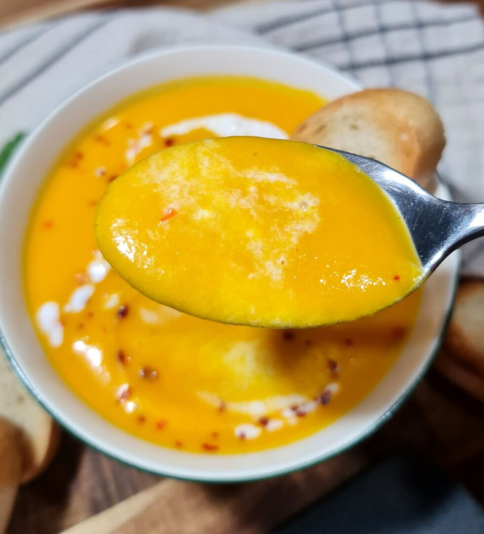 Close-up of a spoonful of Thai coconut pumpkin soup showing its creamy texture and smooth consistency. A spoonful of rich and velvety Thai coconut pumpkin soup.
