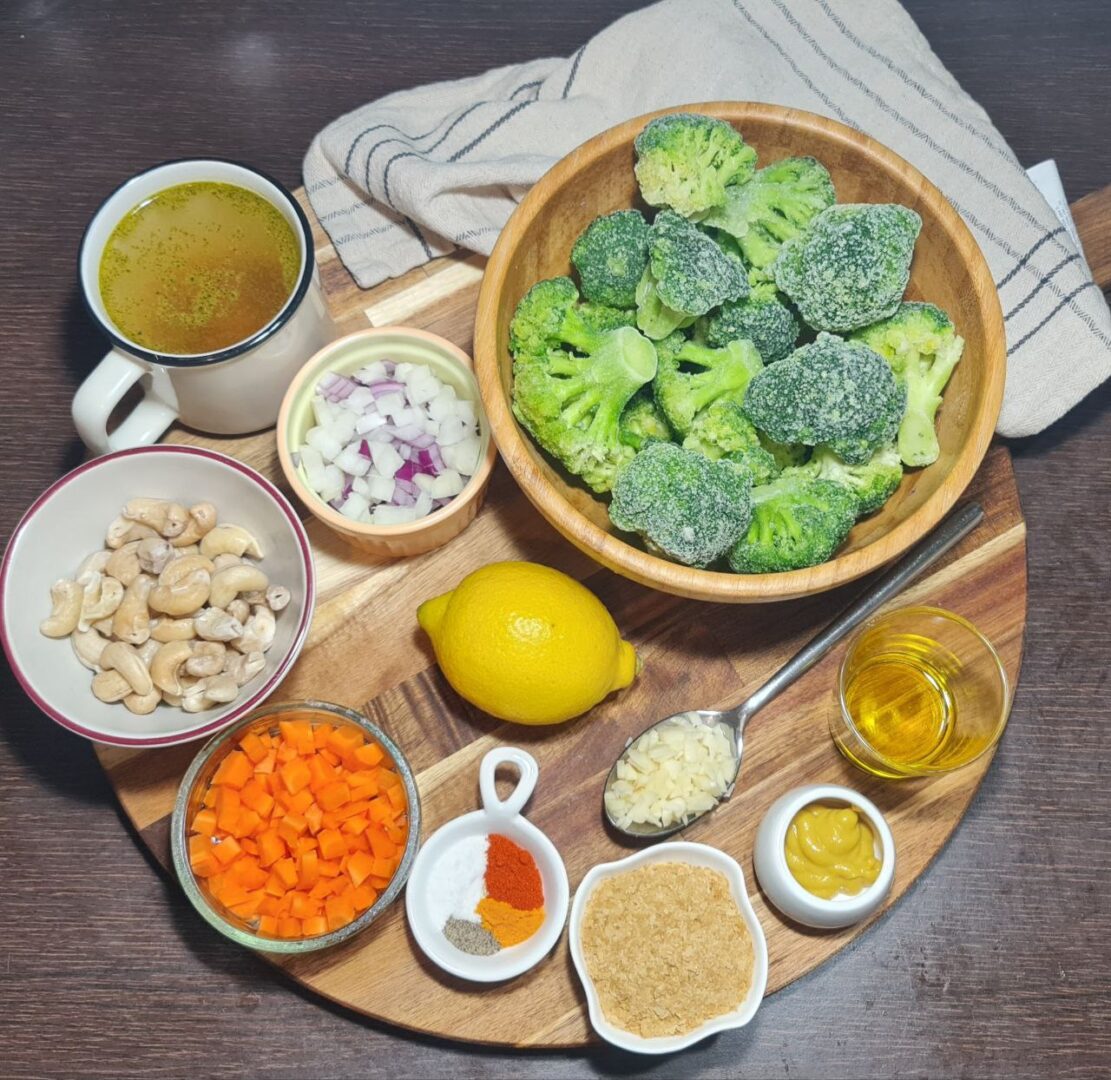 a bowl of broccoli and other ingredients on a wooden board for vegan broccoli cheddar soup.