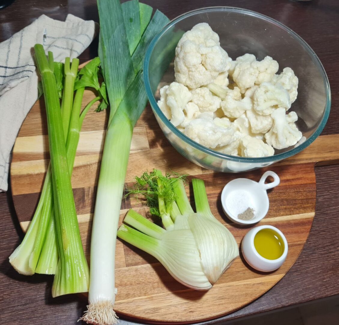 Fresh ingredients for vegan cauliflower fennel soup including cauliflower, fennel, leek, celery, olive oil, salt, and pepper. Fresh, wholesome ingredients for a creamy vegan cauliflower fennel soup.
