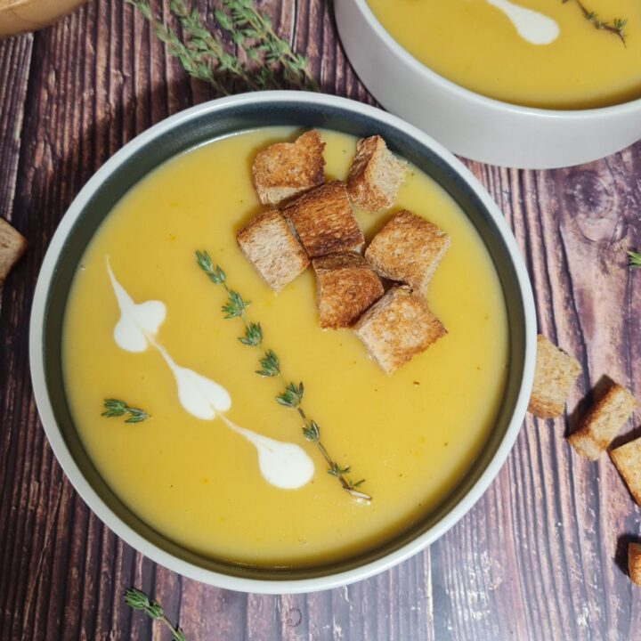 Bowl of vegan creamy roasted garlic potato soup garnished with croutons and thyme. A comforting bowl of vegan creamy roasted garlic soup, topped with croutons and fresh thyme.