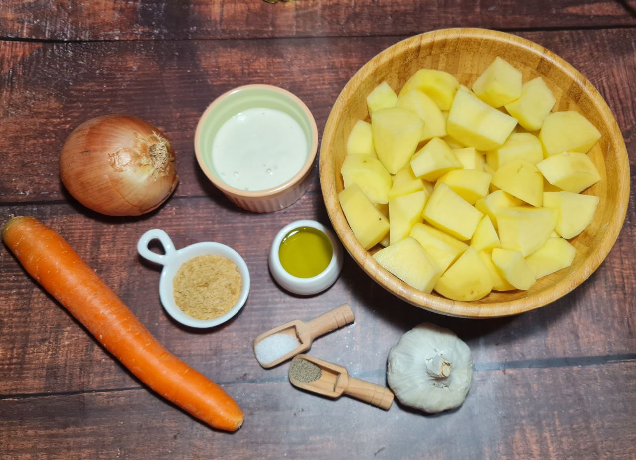 Ingredients for vegan creamy roasted garlic soup, including potatoes, garlic, onion, carrot, and nutritional yeast.  Fresh ingredients for vegan creamy roasted garlic soup, featuring potatoes, garlic, and nutritional yeast.
