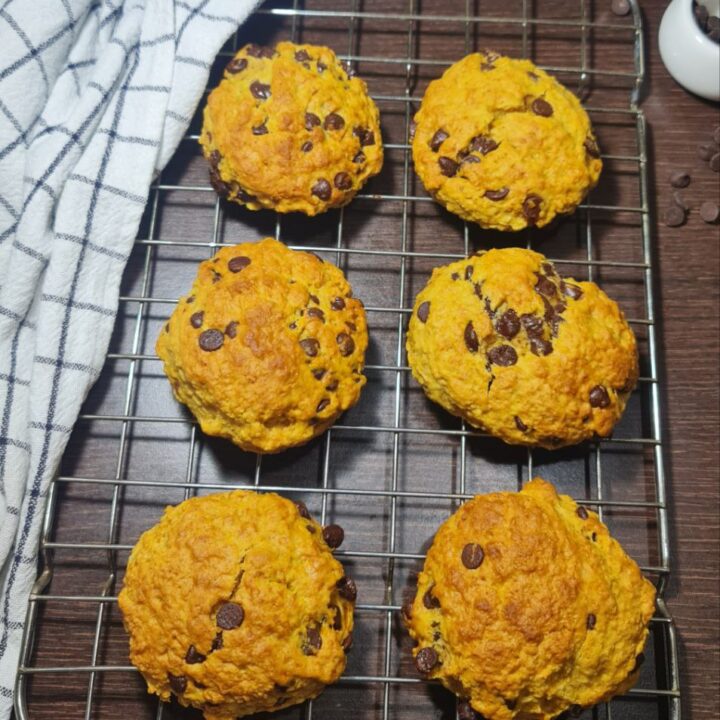 Freshly baked vegan pumpkin chocolate chip cookies cooling on a wire rack. Freshly baked vegan pumpkin chocolate chip cookies cooling on a rack, golden and delicious.