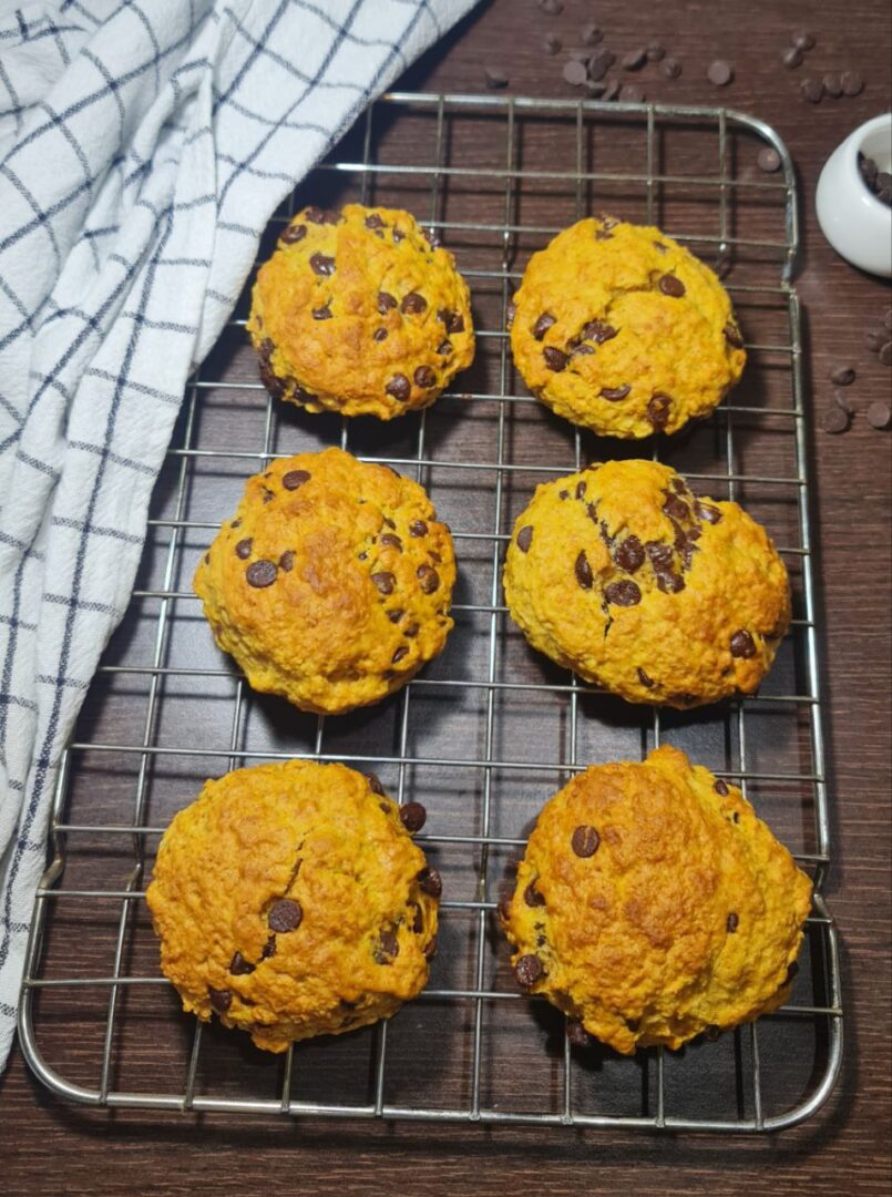 Freshly baked vegan pumpkin chocolate chip cookies cooling on a wire rack. Freshly baked vegan pumpkin chocolate chip cookies cooling on a rack, golden and delicious.