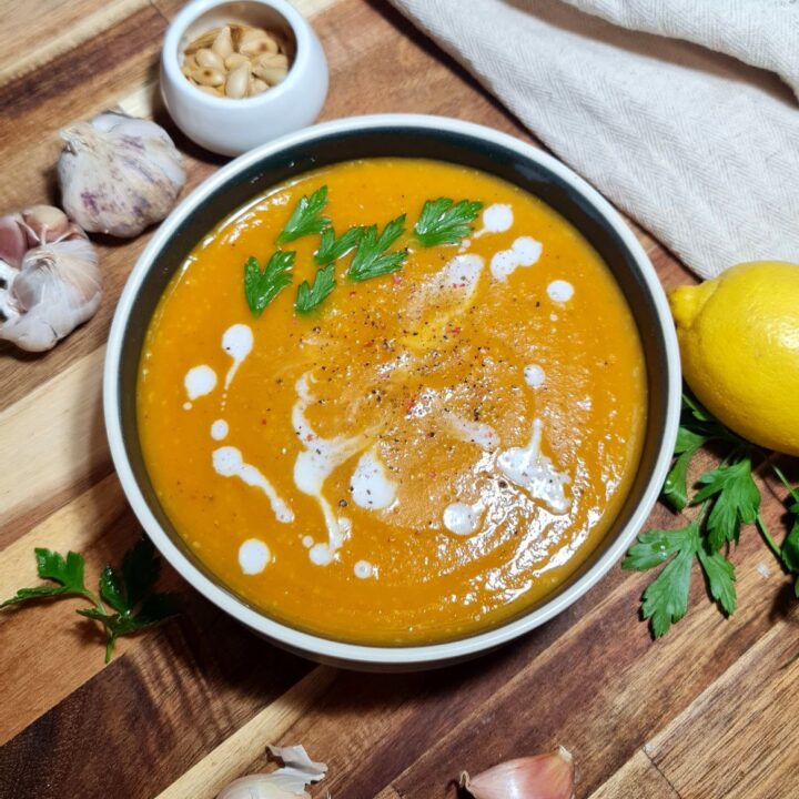 A bowl of creamy butternut squash and sweet potato soup garnished with parsley and coconut milk. Creamy butternut squash and sweet potato soup, topped with fresh parsley and a drizzle of coconut milk.