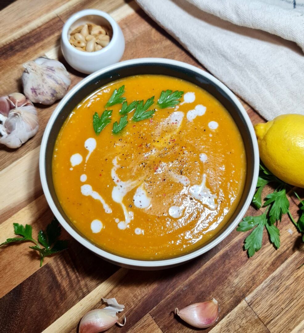 A bowl of creamy butternut squash and sweet potato soup garnished with parsley and coconut milk. Creamy butternut squash and sweet potato soup, topped with fresh parsley and a drizzle of coconut milk.