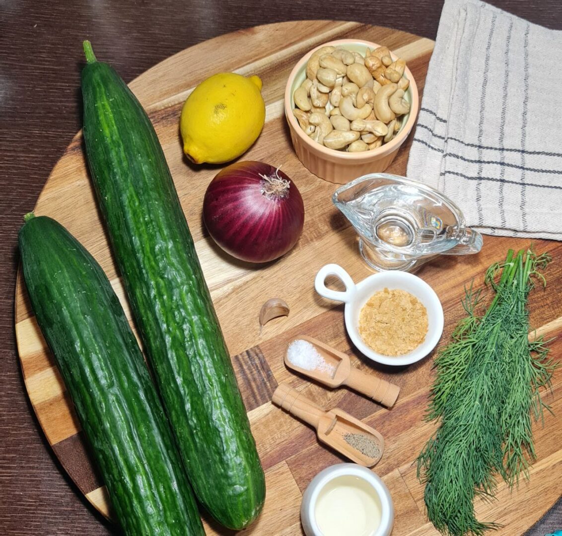  Ingredients for creamy cucumber salad, including cucumbers, red onion, cashews, dill, lemon, garlic, and seasonings. Fresh ingredients for the creamy cucumber salad, including cucumbers, dill, cashews, and lemon.