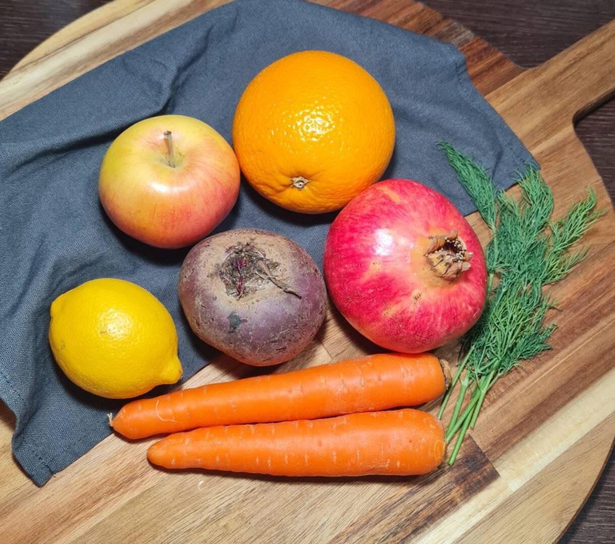 Fresh ingredients for fall beetroot salad including beets, carrots, pomegranate, apple, lemon, orange, and dill. Fresh ingredients used to make a vibrant fall beetroot salad.