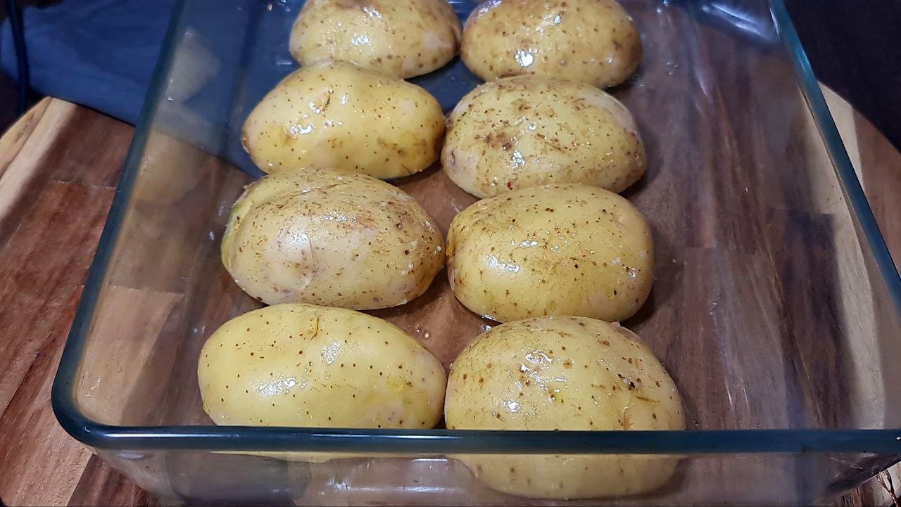 Halved roasted potatoes arranged on a baking tray, with a golden crispy finish. Halved roasted potatoes on a baking tray, perfectly crisped.