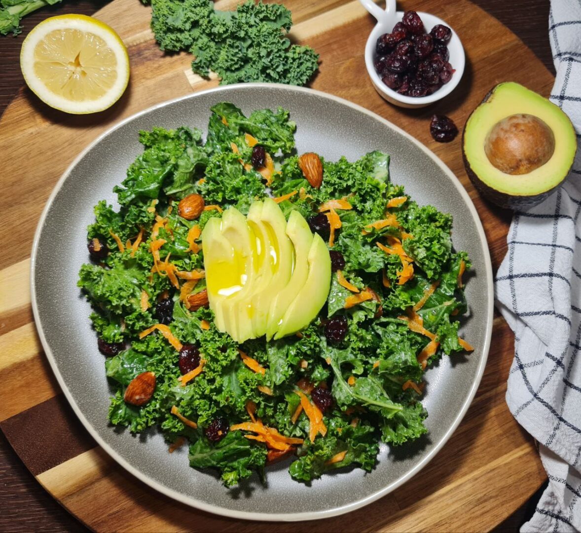 a plate of simple kale salad with avocado and nuts