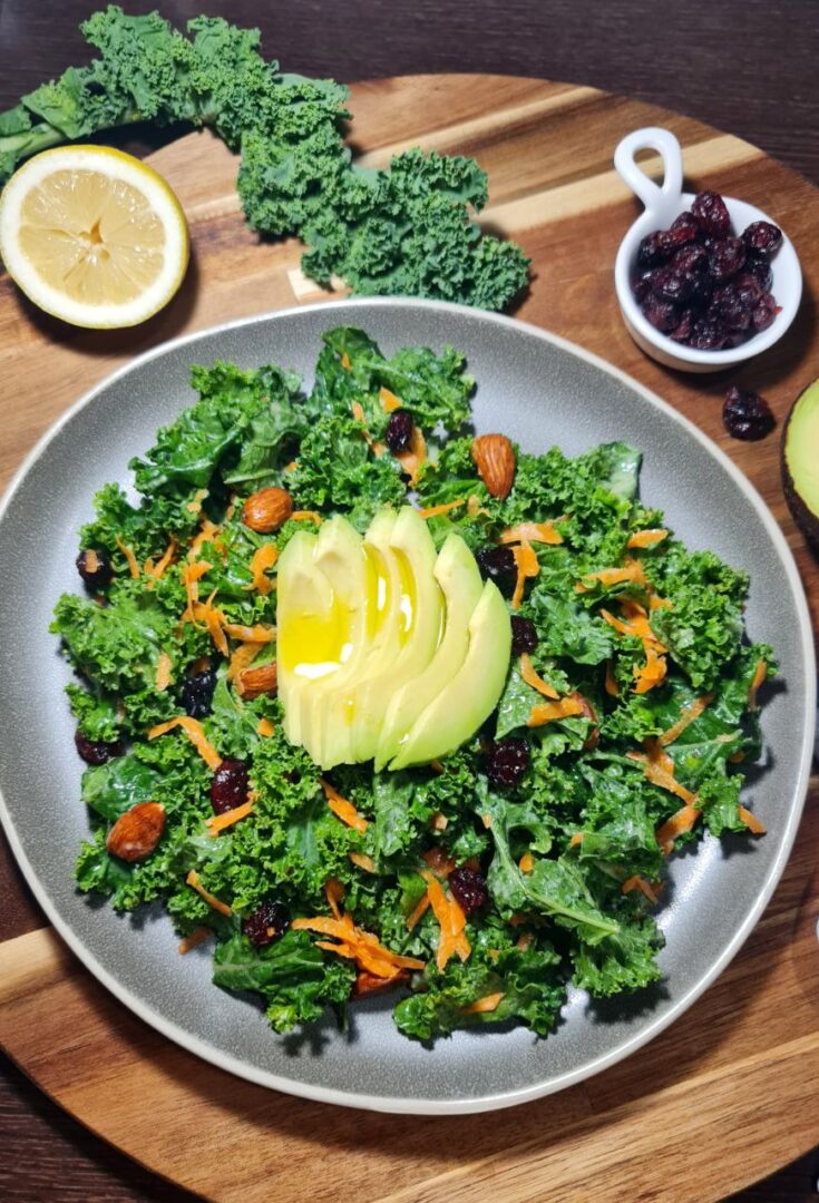 Simple kale salad topped with avocado slices, shredded carrots, almonds, and cranberries. A fresh and nutritious simple kale salad topped with creamy avocado, almonds, and dried cranberries.