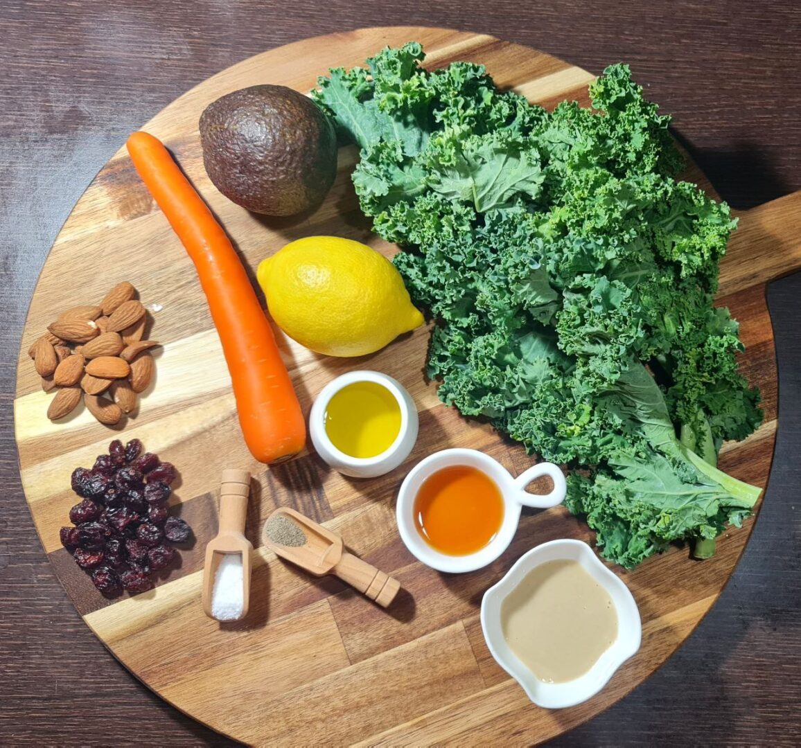  Fresh kale salad ingredients including kale, carrot, lemon, avocado, almonds, and cranberries. Simple kale salad ingredients: kale, avocado, lemon, carrot, almonds, cranberries, and a lemon tahini dressing.
