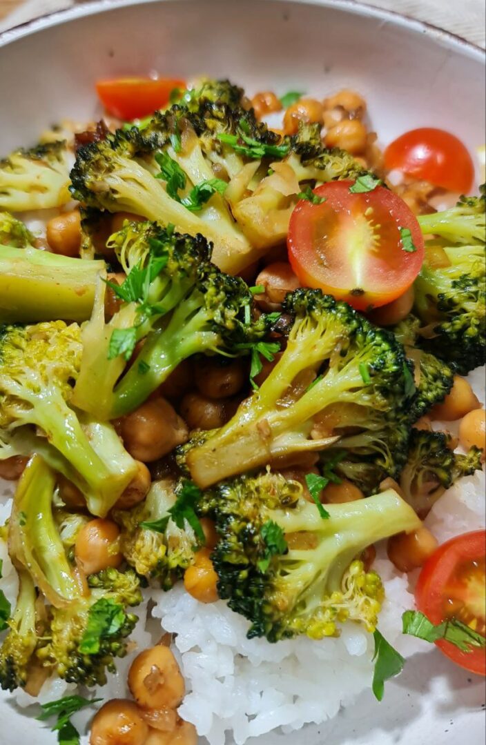 Close-up of vegan broccoli stir fry with chickpeas, cherry tomatoes, and fresh parsley on a bed of rice. A vibrant close-up of vegan broccoli stir fry with chickpeas and cherry tomatoes served over rice.
