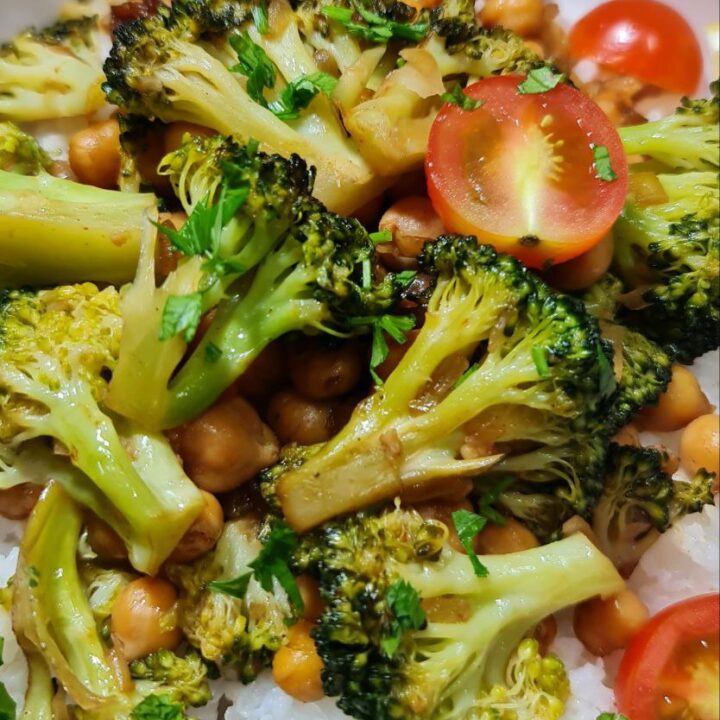 Close-up of vegan broccoli stir fry with chickpeas, cherry tomatoes, and fresh parsley on a bed of rice. A vibrant close-up of vegan broccoli stir fry with chickpeas and cherry tomatoes served over rice.