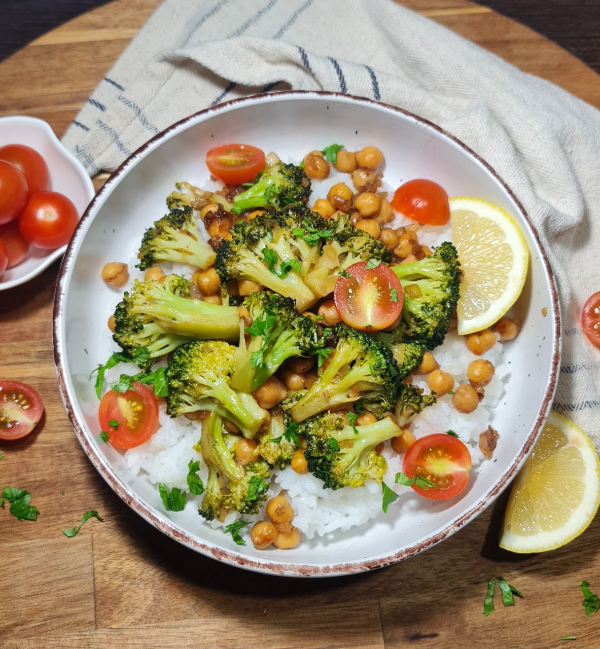 Vegan broccoli stir fry with chickpeas, cherry tomatoes, and lemon slices served on rice. A wholesome vegan broccoli stir fry with chickpeas, cherry tomatoes, and lemon slices over rice.