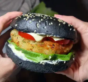 Vegan potato burger with charcoal bun, lettuce, tomato, and vegan mayonnaise. Delicious vegan potato burger with a crispy patty, fresh lettuce, tomato, and vegan mayo on a charcoal bun.