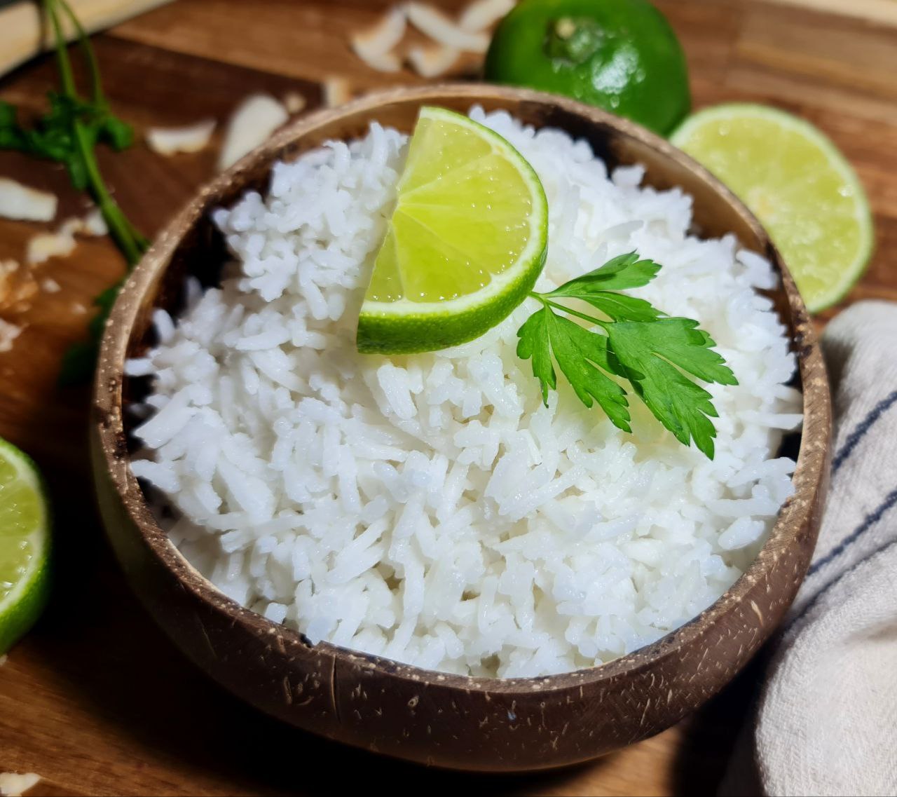 A bowl of coconut rice garnished with a lime wedge and a sprig of parsley.