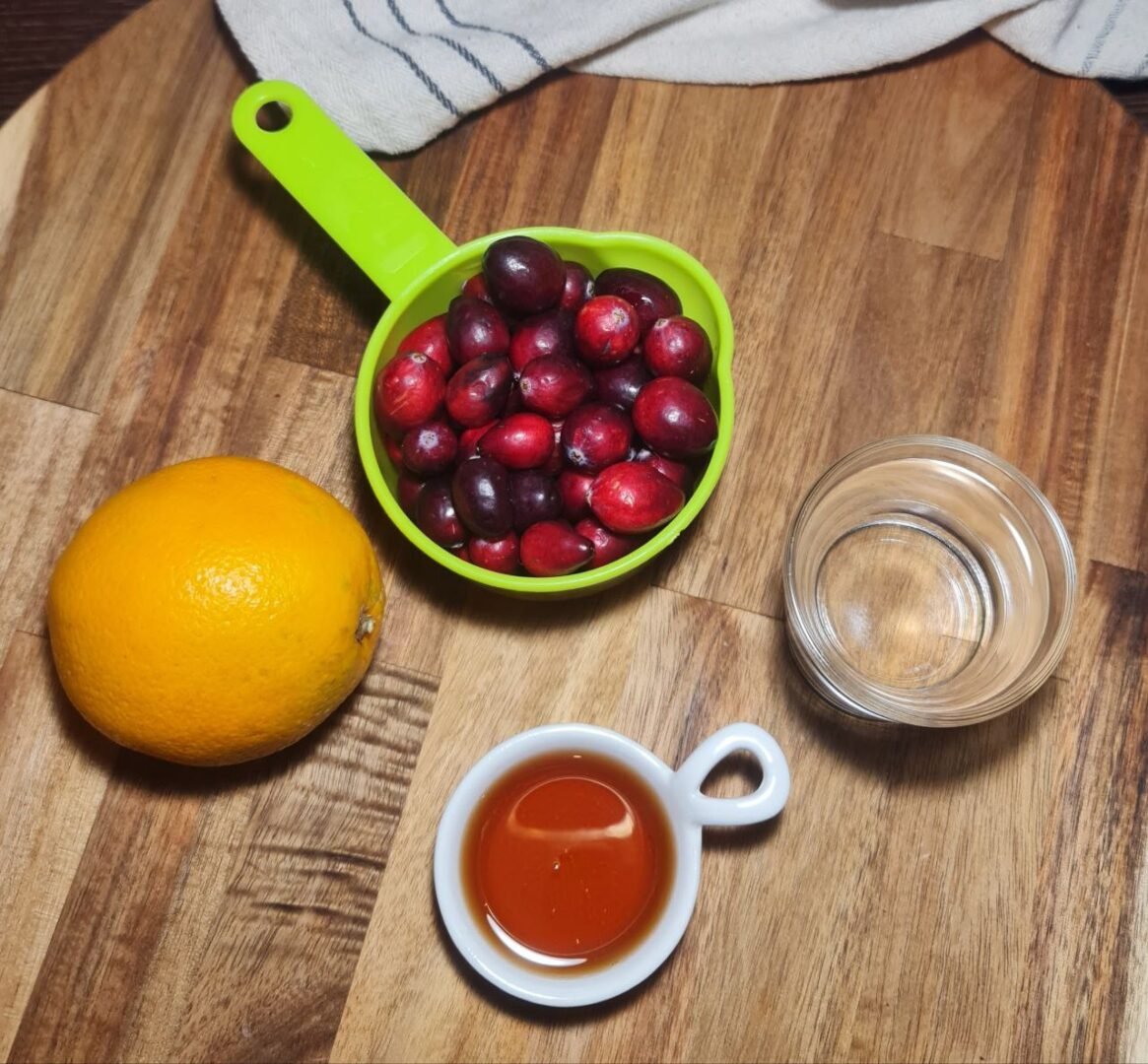 a bowl of cranberries and a glass of water next to a cup of liquid